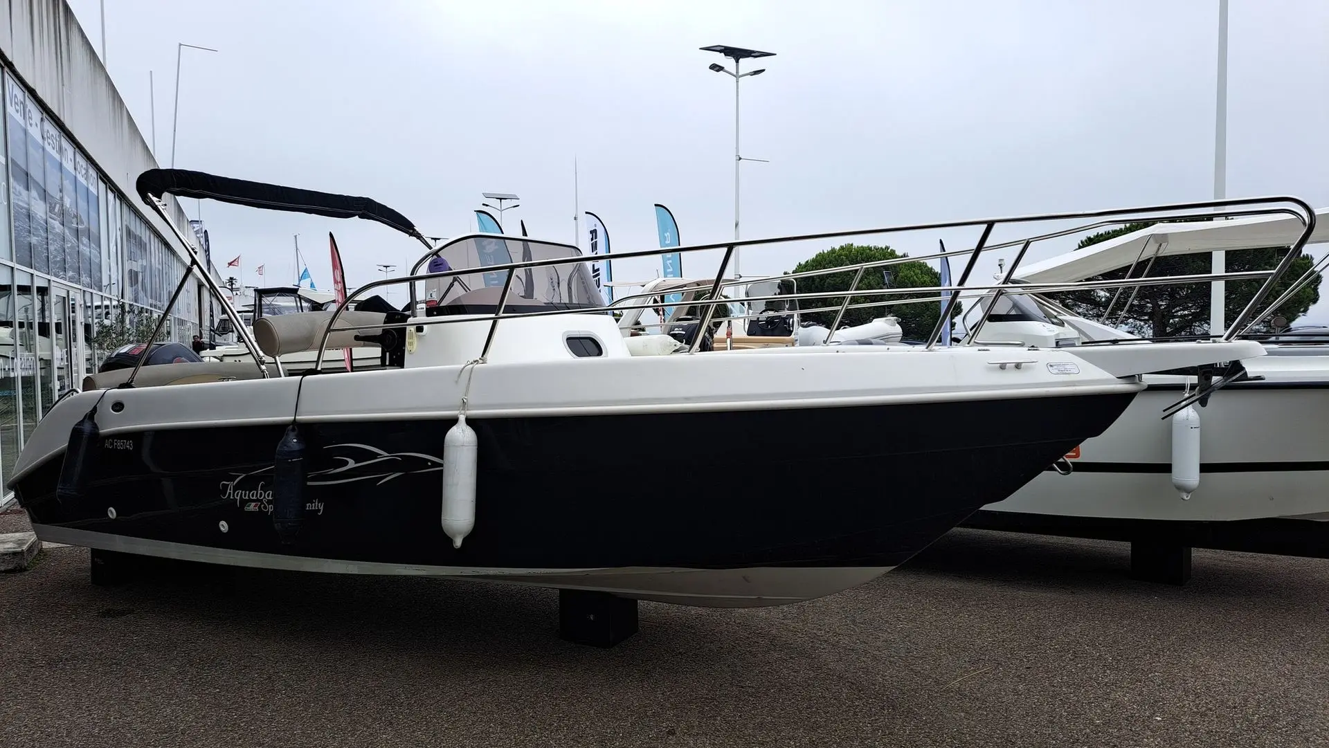 Aquabat Sport Infinity 650 — Bateau à moteur blanc et noir présenté sur berceau dans un espace d’exposition.