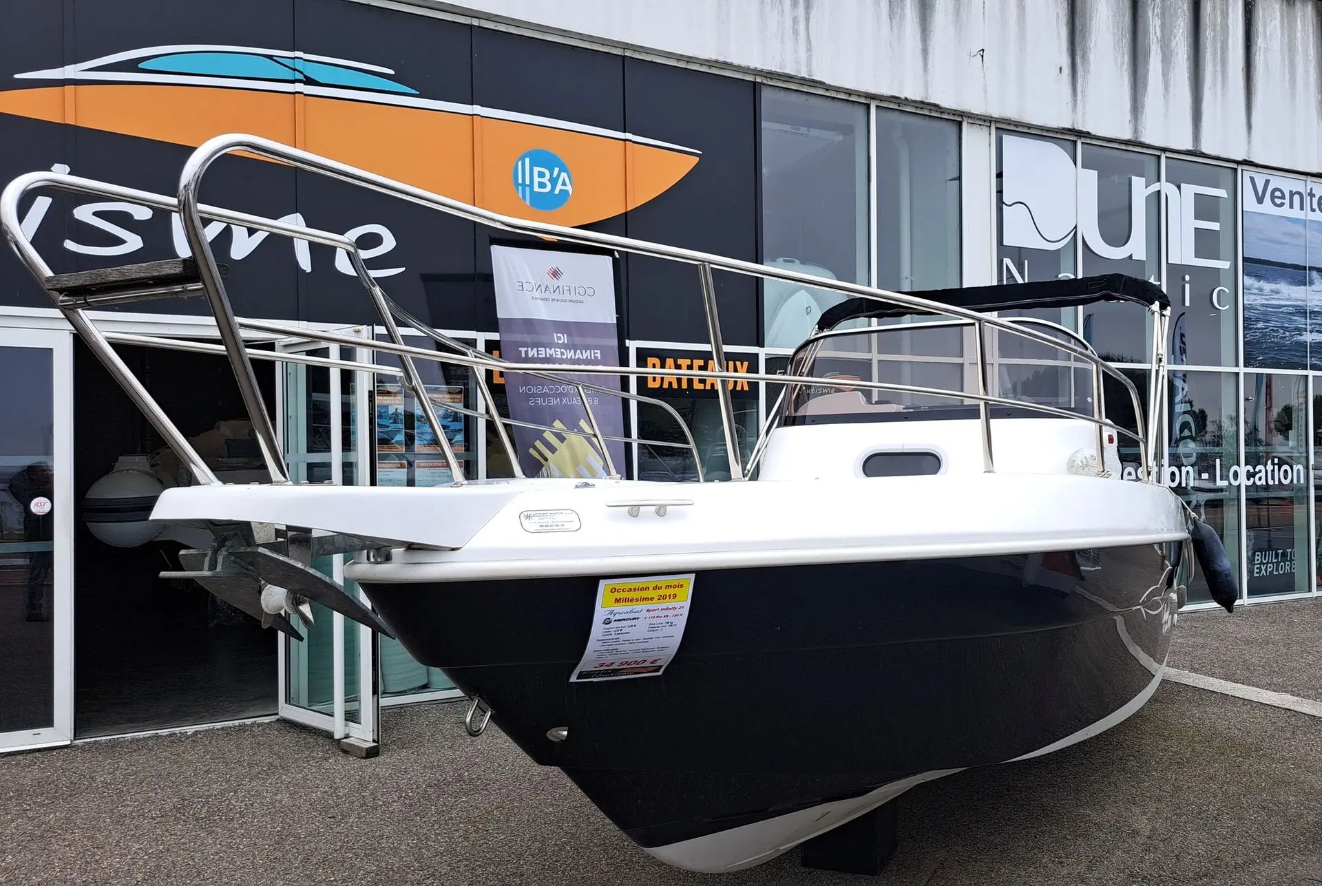 Aquabat Sport Infinity 650 — Bateau à coque noire exposé devant la vitrine d’un concessionnaire.