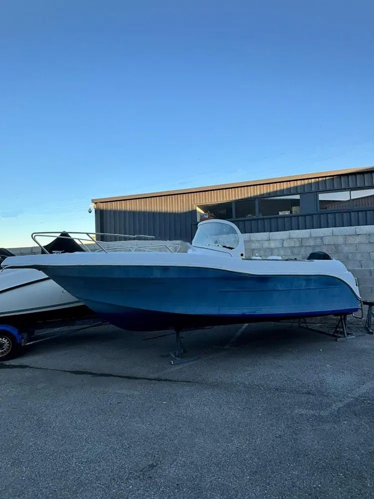 Quicksilver 630 Open Commander — Bateau à moteur bleu et blanc photographié de profil sur sa remorque.