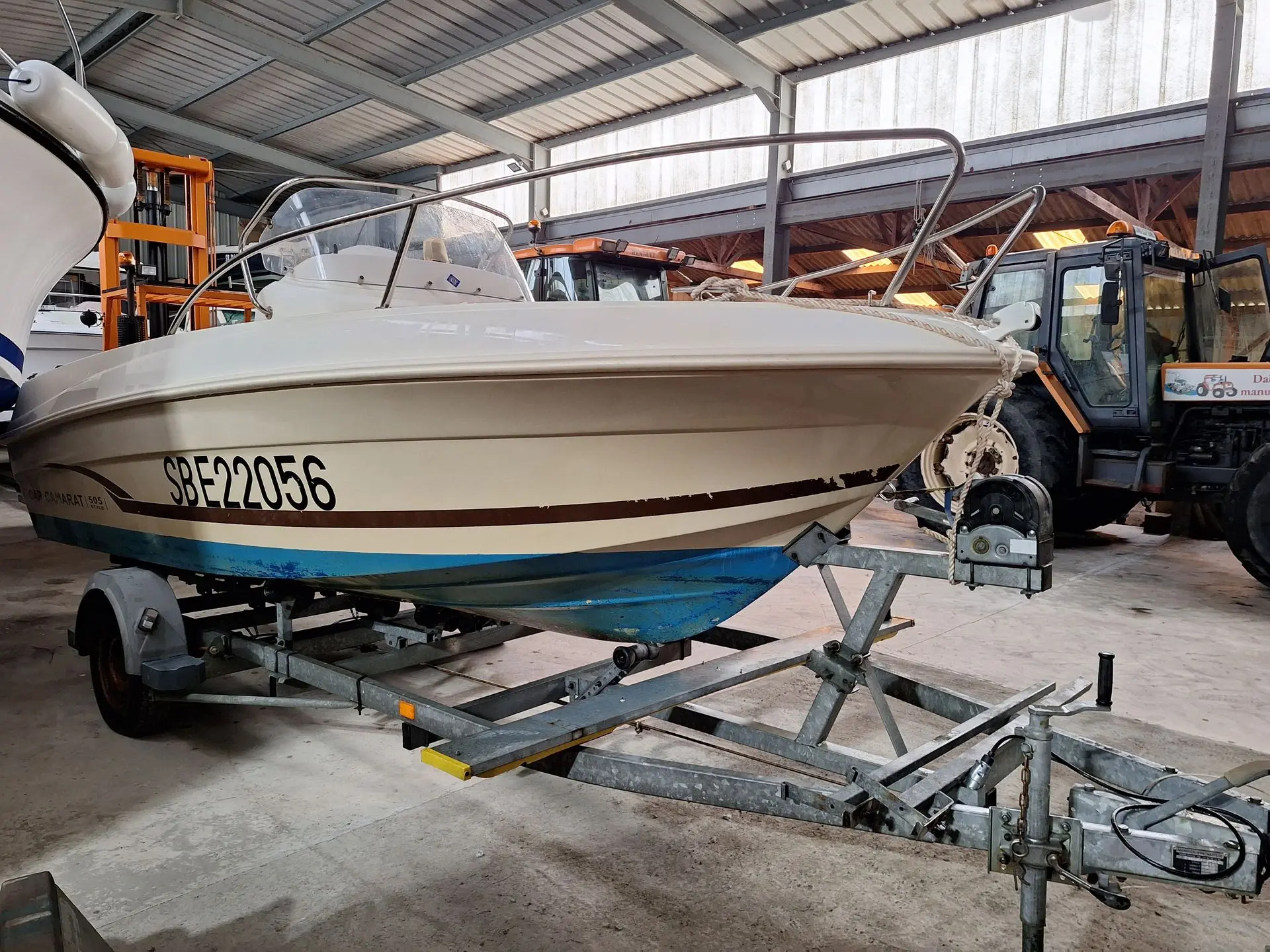 Jeanneau Cap Camarat 505 — Bateau à moteur blanc posé sur une remorque dans un hangar.