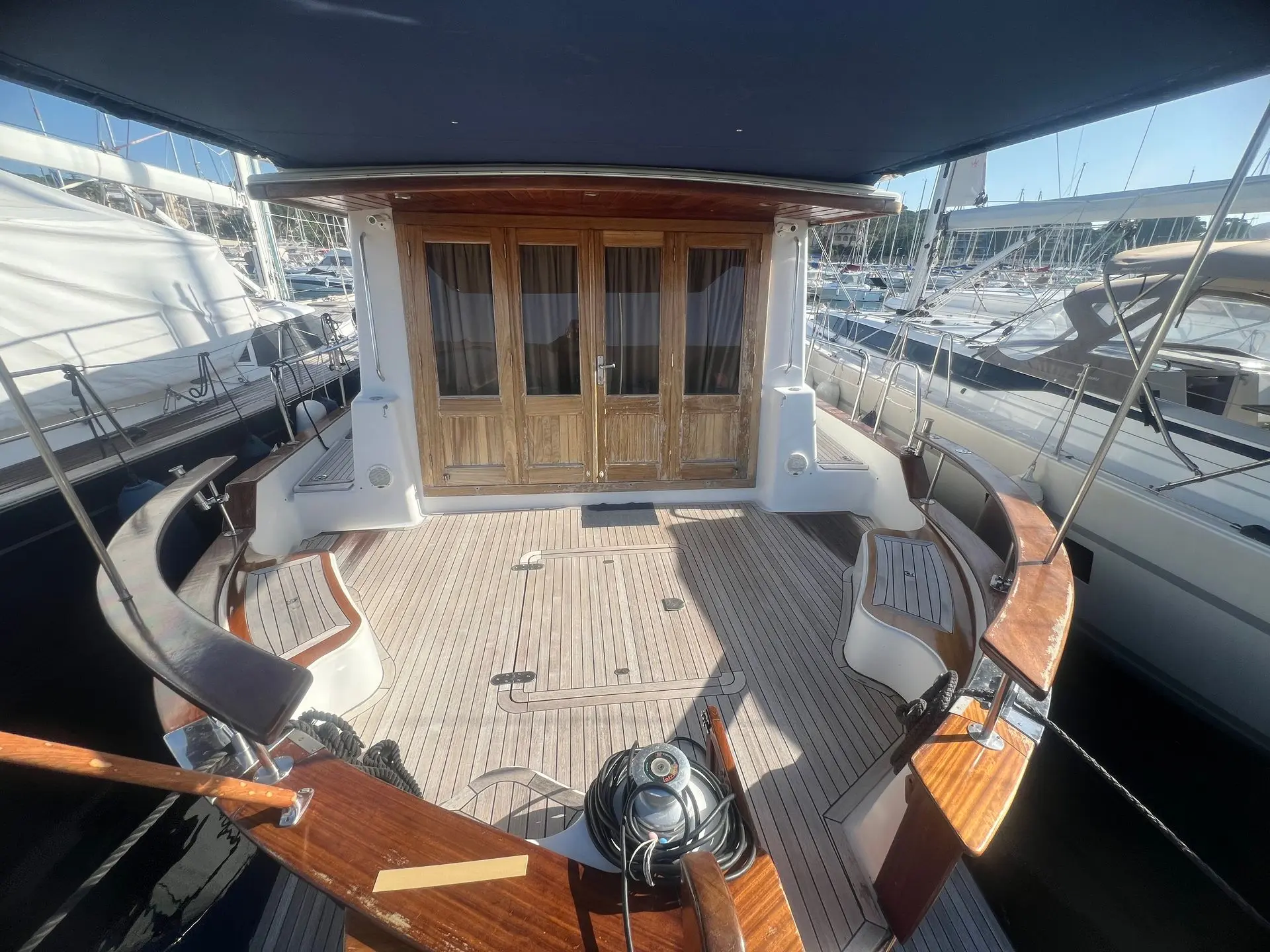 Menorquin 160 — Cockpit arrière en teck avec portes vitrées et mobilier en bois.