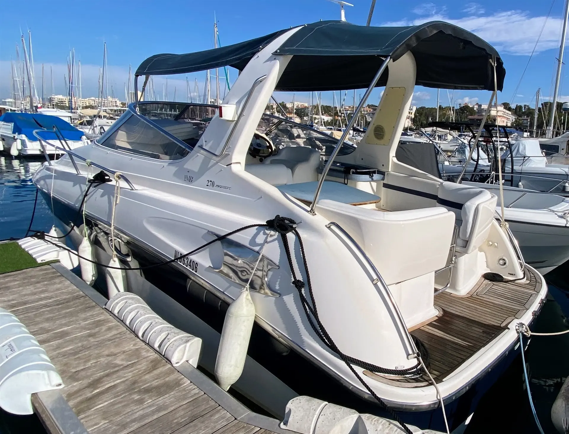 Bavaria 270 — Vedette blanche amarrée dans une marina, équipée d'un taud sombre et d'un cockpit ouvert.