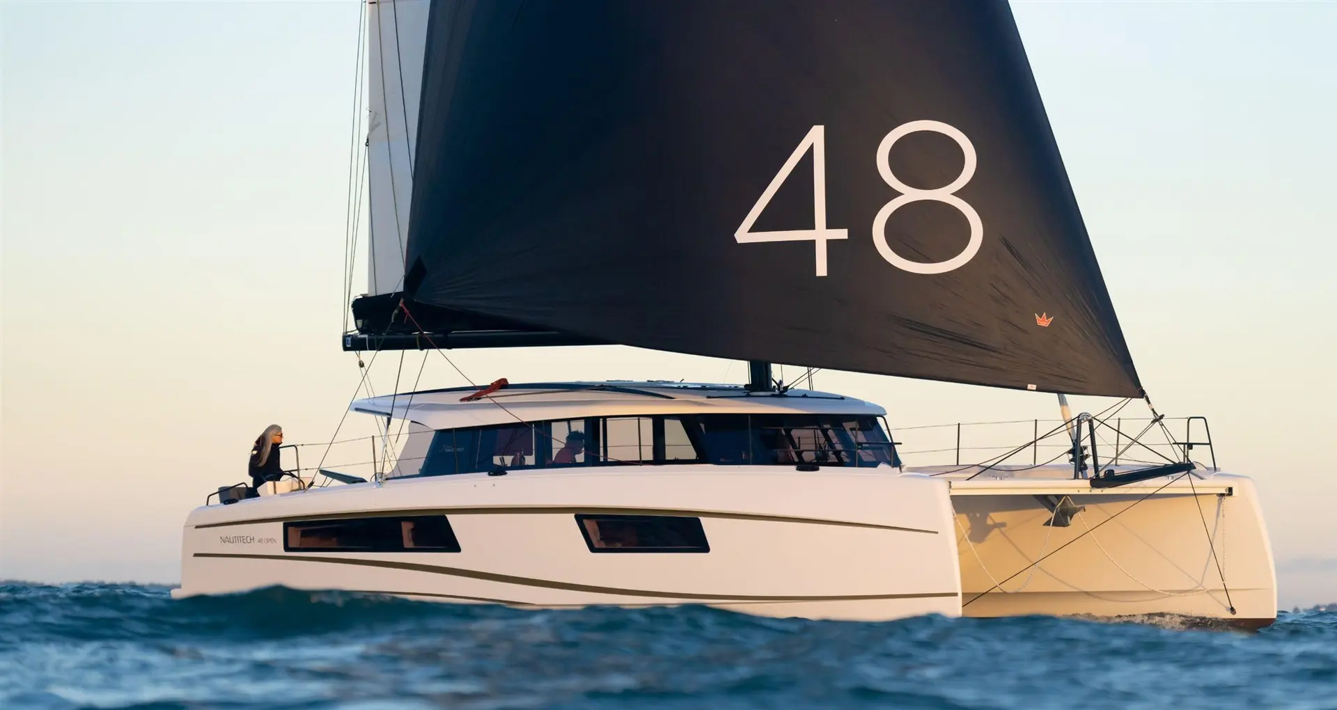 Nautitech 48 Open — Catamaran blanc vu de profil sur une mer légèrement agitée, sous voile noire.
