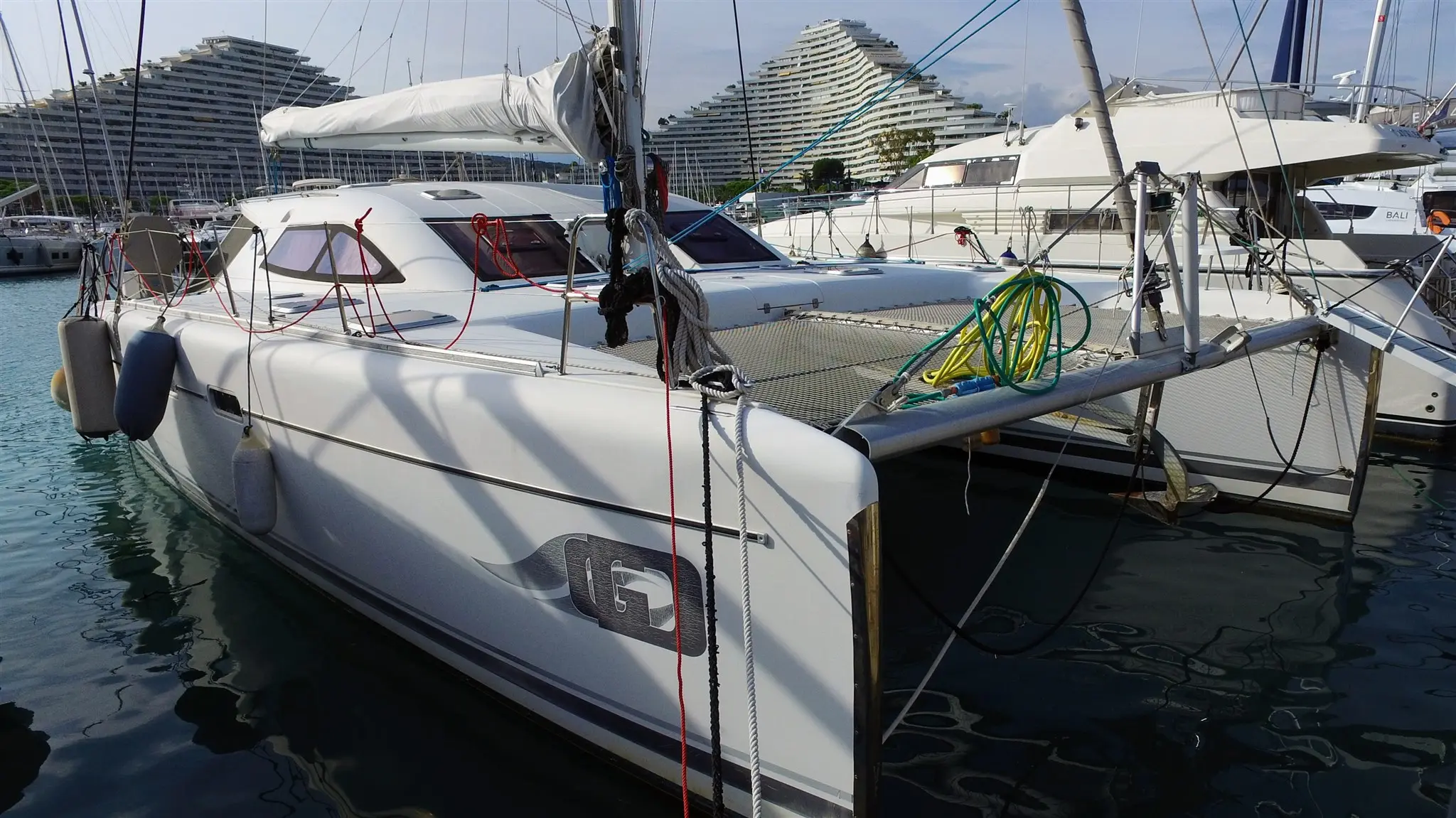 Nautitech 47 — Catamaran blanc amarré dans une marina, entouré d'autres bateaux.
