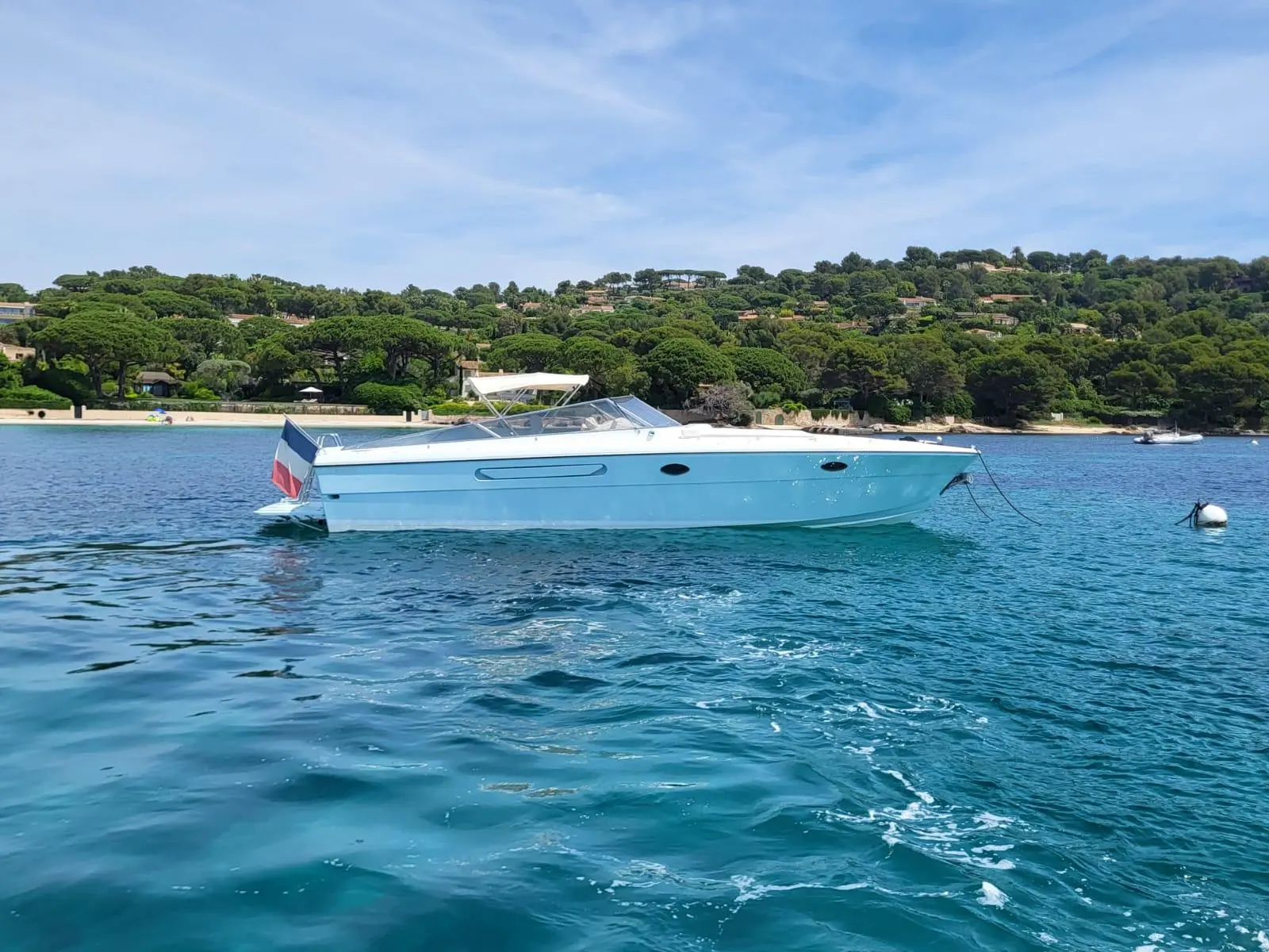 Itama 38 — Bateau à moteur blanc vu de profil, au mouillage dans une baie côtière.