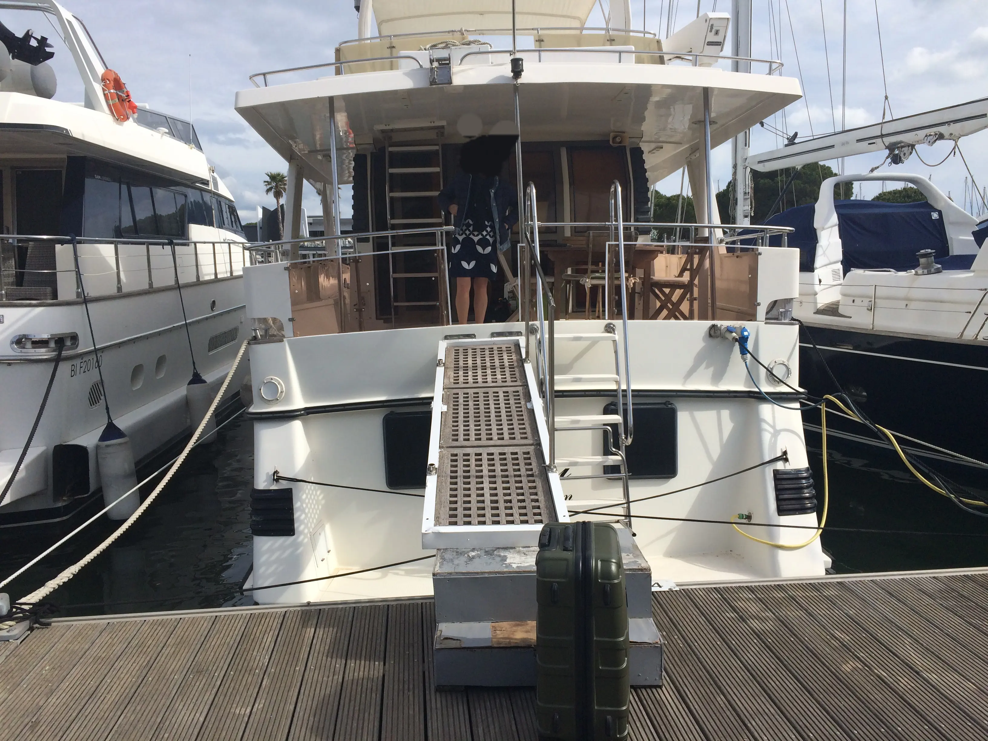 Edership 60 — Vue arrière d’un bateau amarré, avec passerelle et espace extérieur couverts.