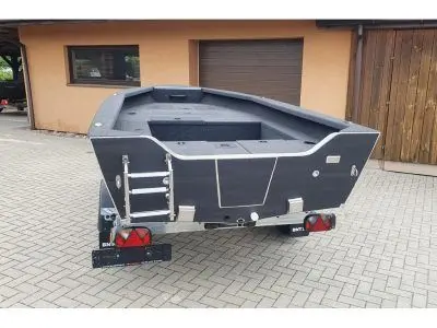 Brema 430v Probass — Petit bateau à coque sombre présenté sur une remorque devant un bâtiment.