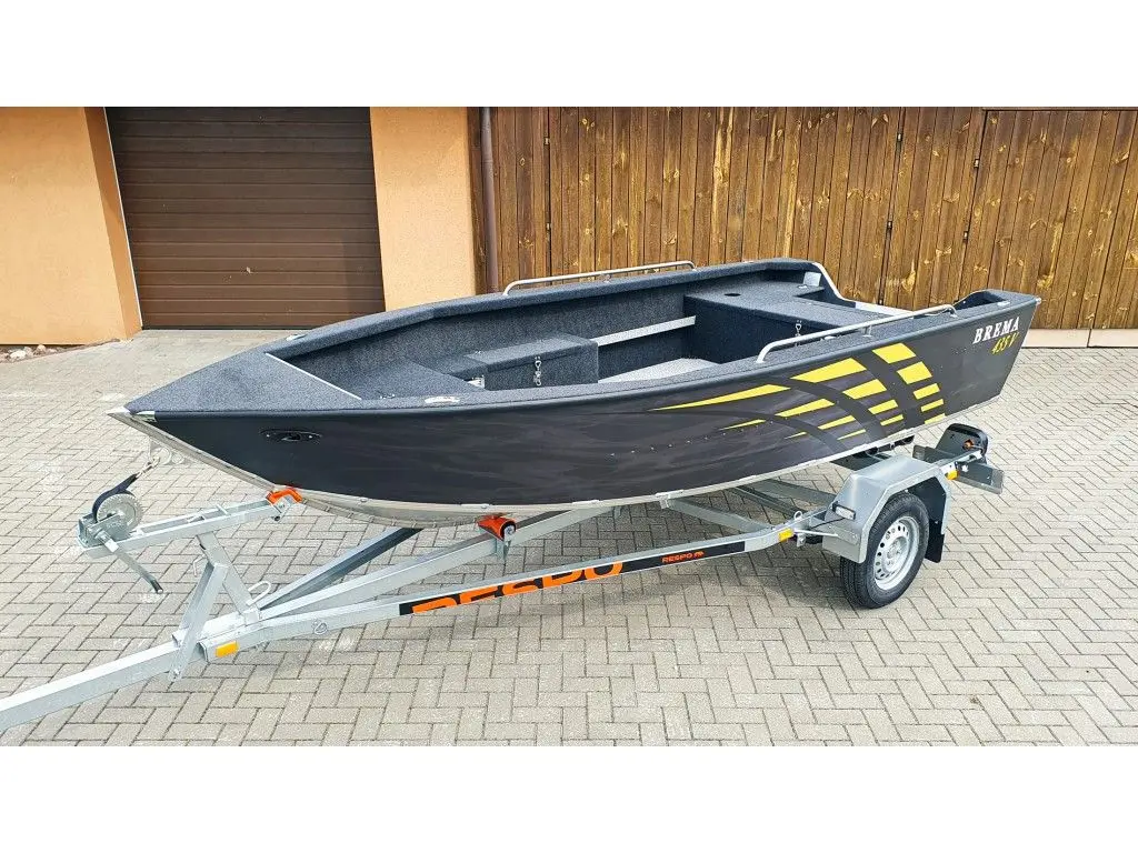 Brema 435V Fishing — Bateau ouvert noir et jaune présenté sur une remorque devant un bâtiment.