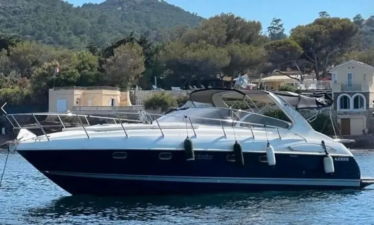 Airon Marine 388 — Bateau à moteur vu de profil sur l’eau, amarré devant une rive boisée.