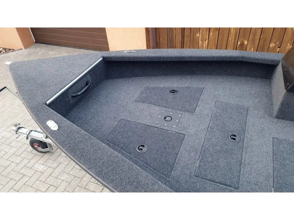 Brema 450V Pro Bass — Vue du pont avant d’un bateau ouvert avec plancher moquetté et trappes de rangement.