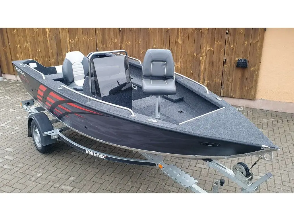 Brema 480V Fishing Pro — Bateau à moteur ouvert gris et noir posé sur sa remorque devant une porte en bois.