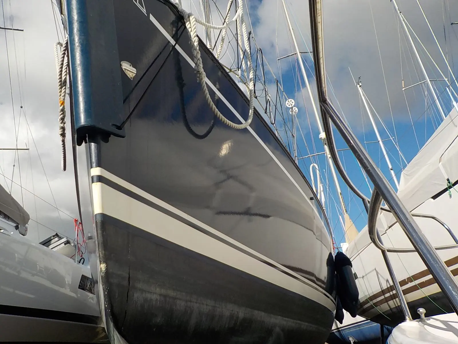 Dehler 29 — Vue en contre-plongée de la coque d’un voilier amarré entre d’autres bateaux.