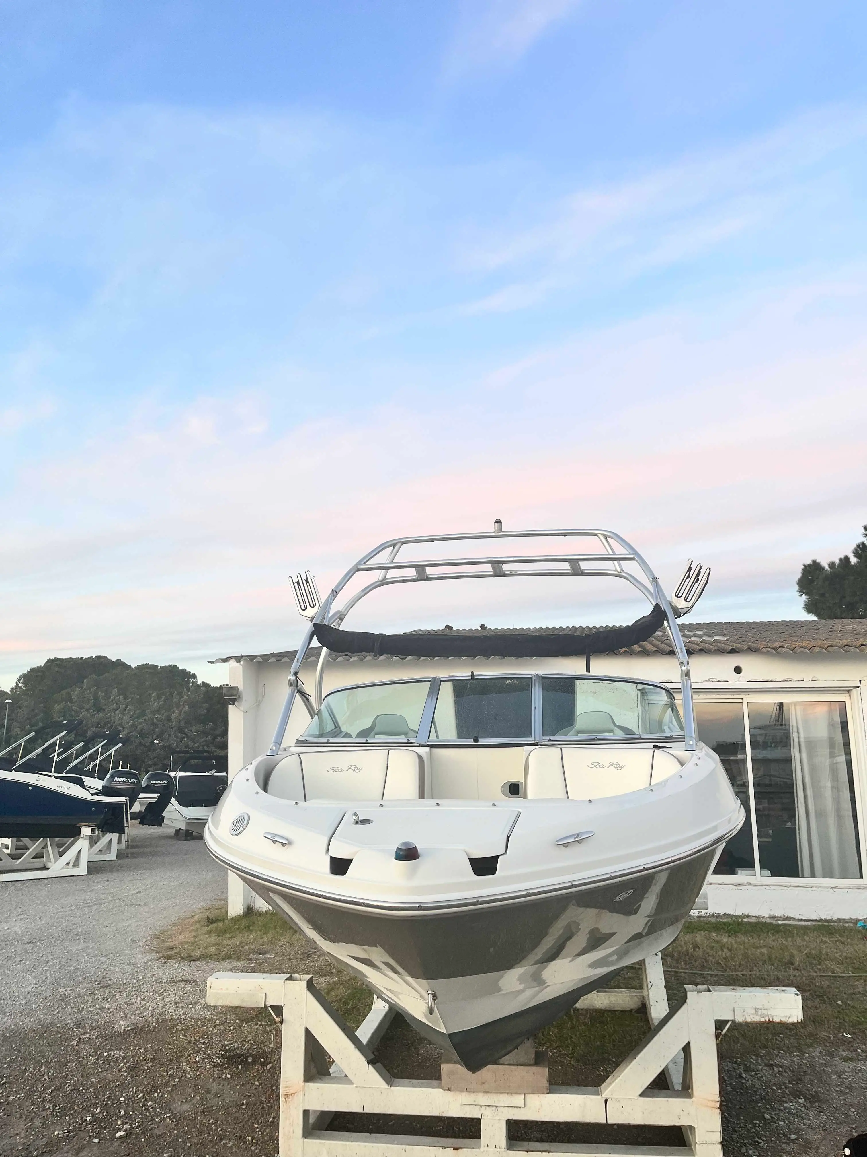 Sea Ray 210 — Bateau à moteur blanc photographié de face sur sa remorque, devant un bâtiment.