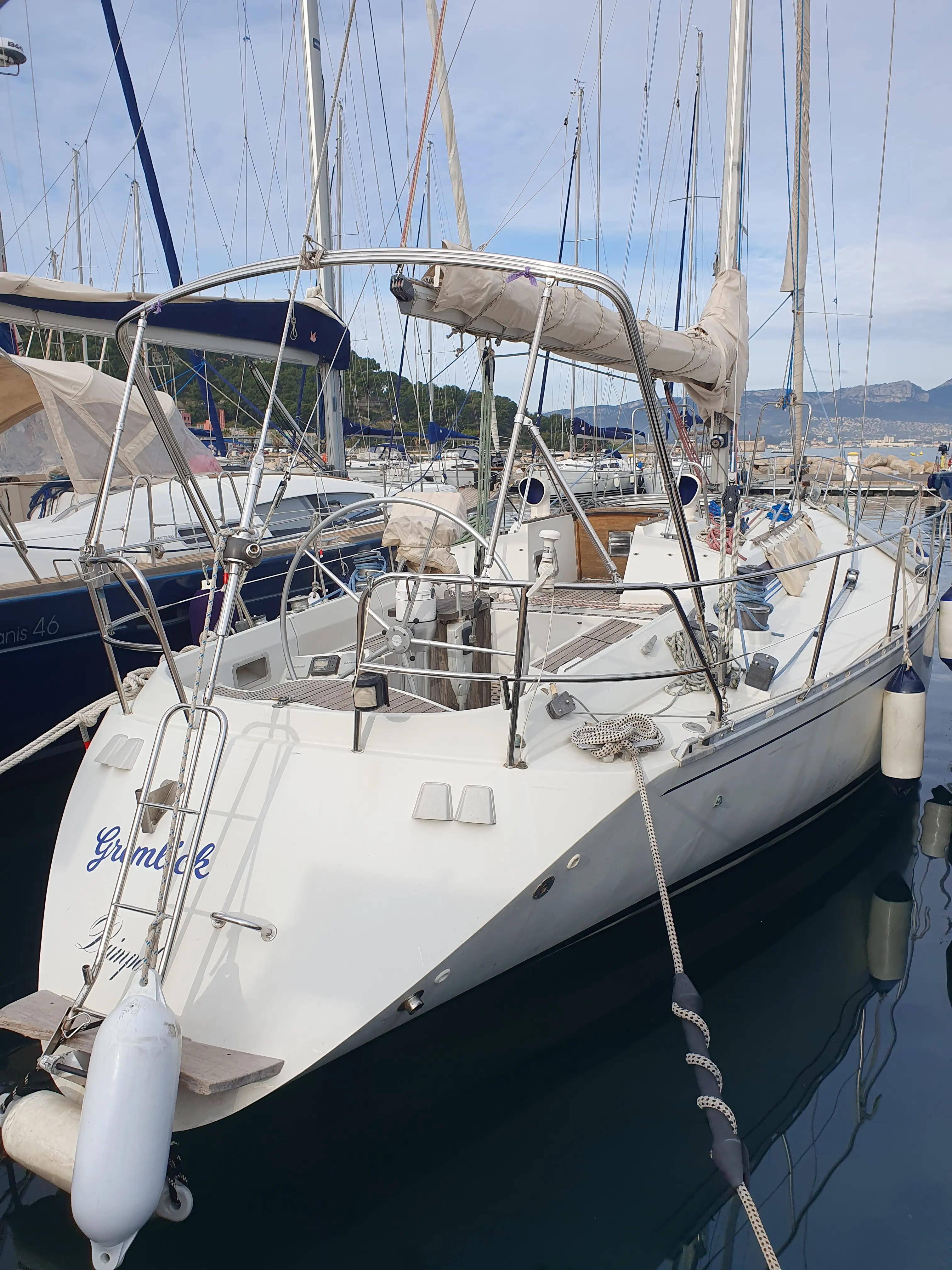 Beneteau First 435 — Voilier blanc amarré, vu de trois quarts avant dans un port de plaisance.