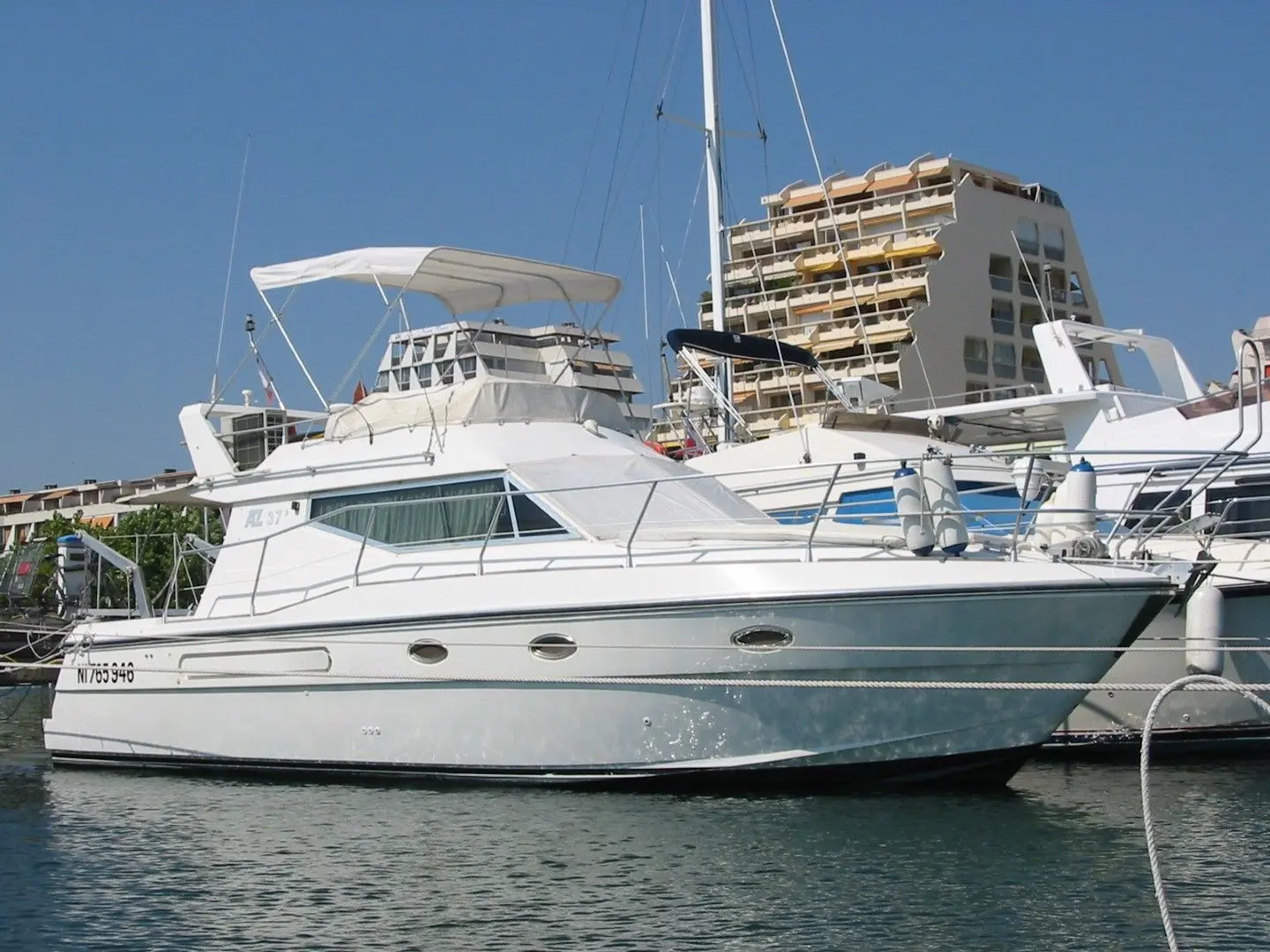 Azimut 37 — Bateau à moteur blanc photographié de profil dans un port, amarré devant des immeubles.