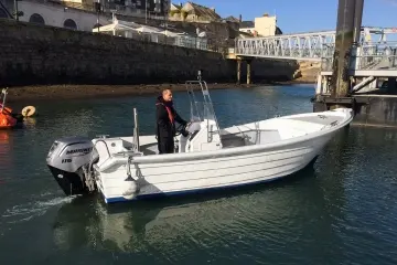 Fibramar Pescador 600 Open — Bateau à moteur blanc vu de trois quarts dans un canal, avec une personne à bord.