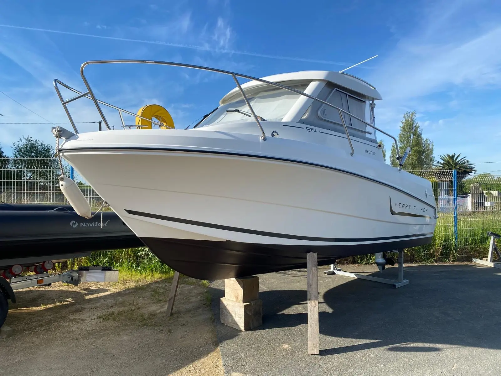 Jeanneau Merry Fisher 595 — Bateau à moteur blanc présenté sur bers, photographié de trois quarts avant.
