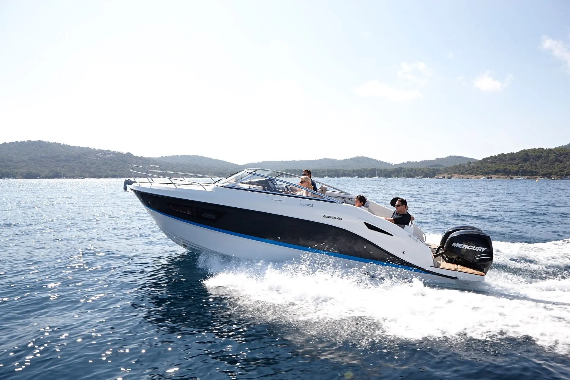 Quicksilver Activ 805 — Bateau à moteur naviguant au large dans une baie, avec trois personnes à bord.