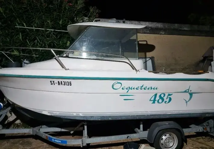 Ocqueteau 485 — Bateau à moteur blanc vu de profil sur une remorque, photographié de nuit.