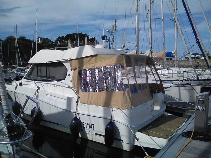 Jeanneau Merry Fisher 815 — Bateau à moteur blanc amarré dans un port, vu de trois quarts arrière.