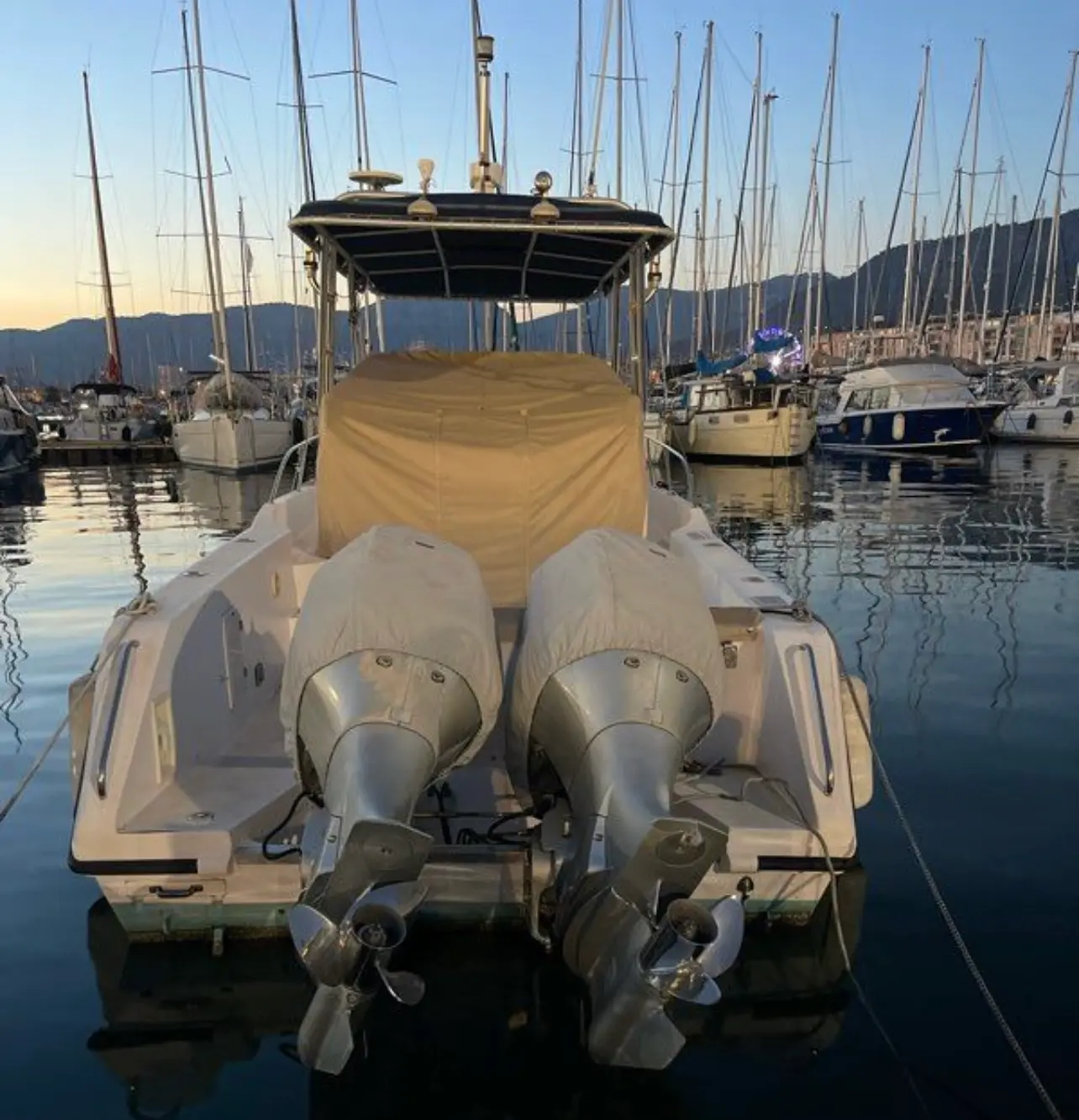 Gulf Craft 31 WA — Vue arrière d’un bateau bimoteur amarré dans une marina, avec tauds de protection.