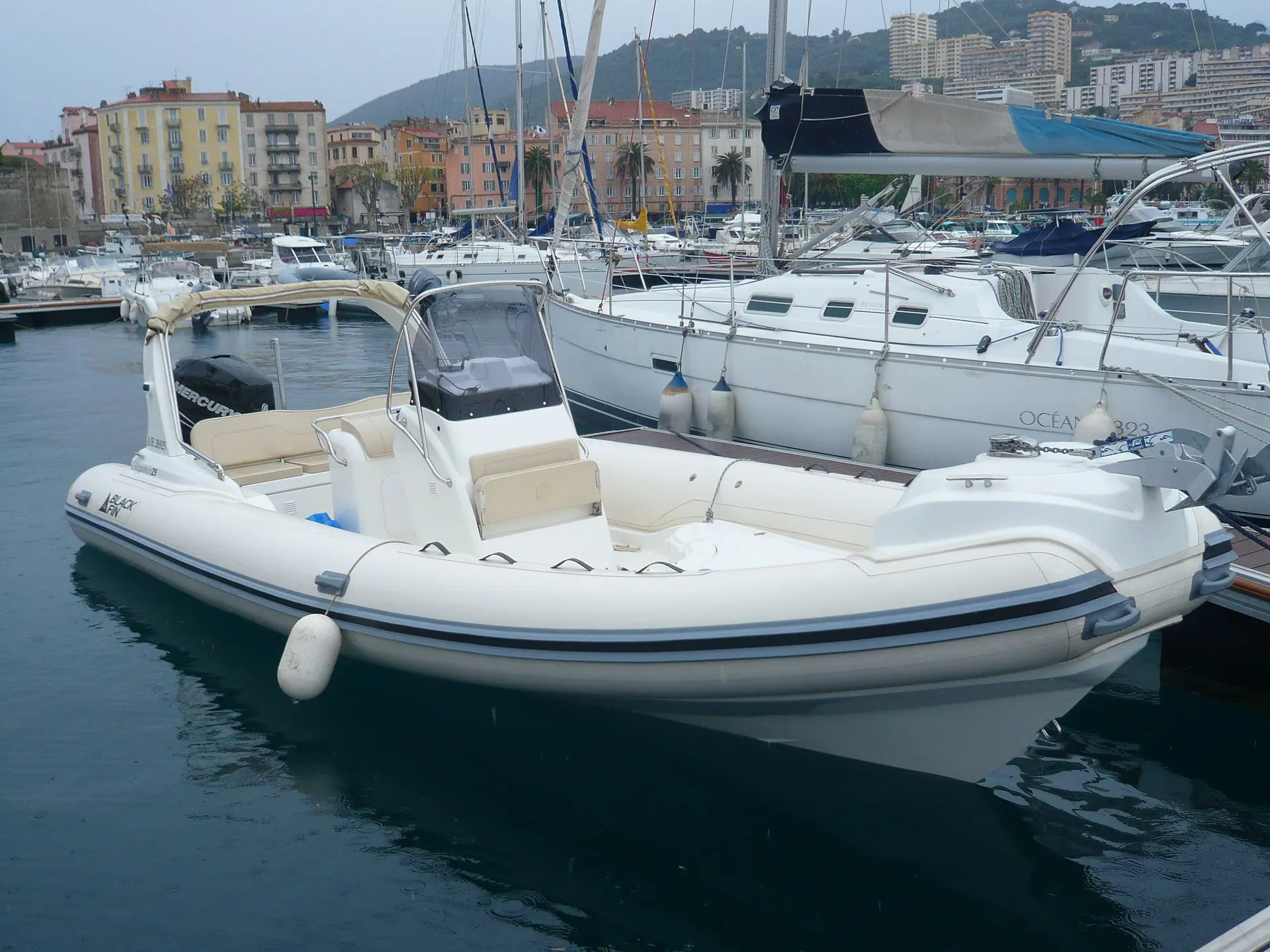 Black Fin 25 — Bateau semi-rigide blanc amarré dans un port, vu de trois quarts.