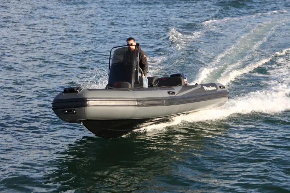 Adventure Vesta 550 Profish — Semi-rigide gris naviguant sur l’eau avec un homme à la barre.
