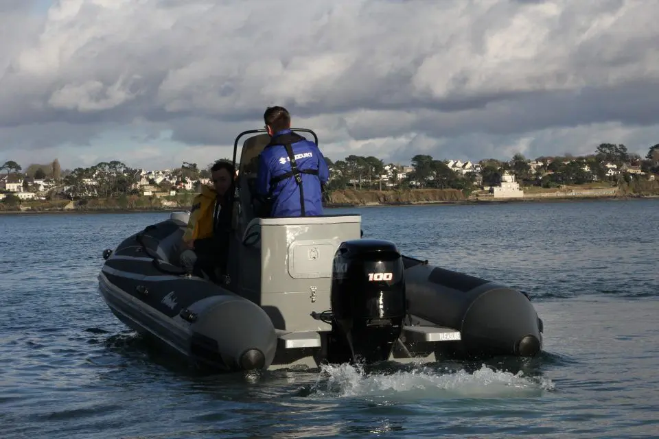 Adventure Vesta 585 Profish — Bateau pneumatique vu de l’arrière, avec deux personnes à bord et un moteur hors-bord.