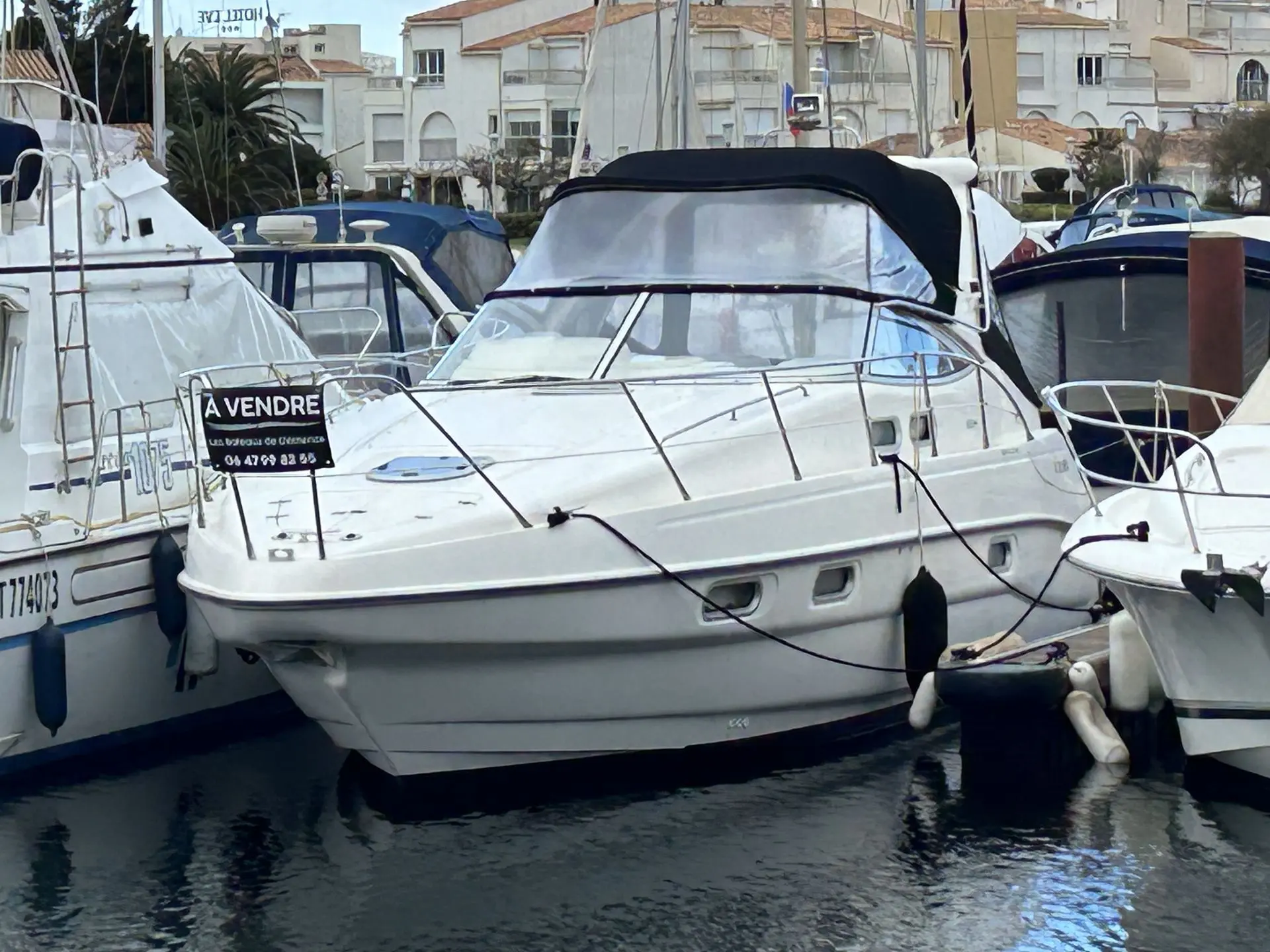 Sealine S 34 — Un bateau à moteur blanc est photographié de trois-quarts avant, amarré dans un port.