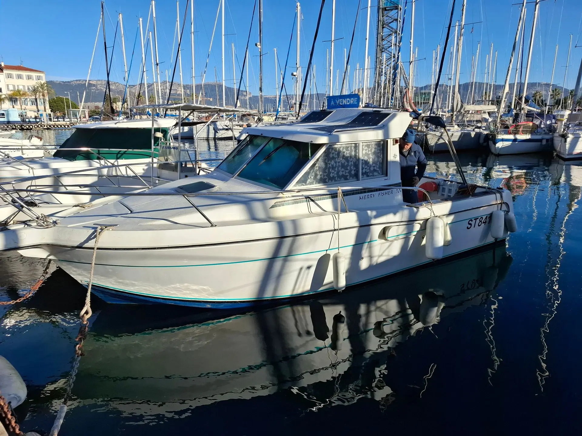 Jeanneau Merry Fisher 700 — Bateau à moteur amarré dans un port, photographié de trois quarts.