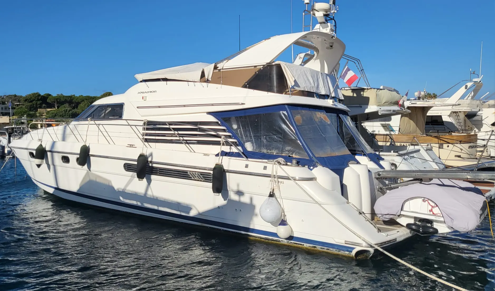 Fairline Squadron 56 — Bateau à moteur blanc amarré dans une marina, vu de trois quarts avant.