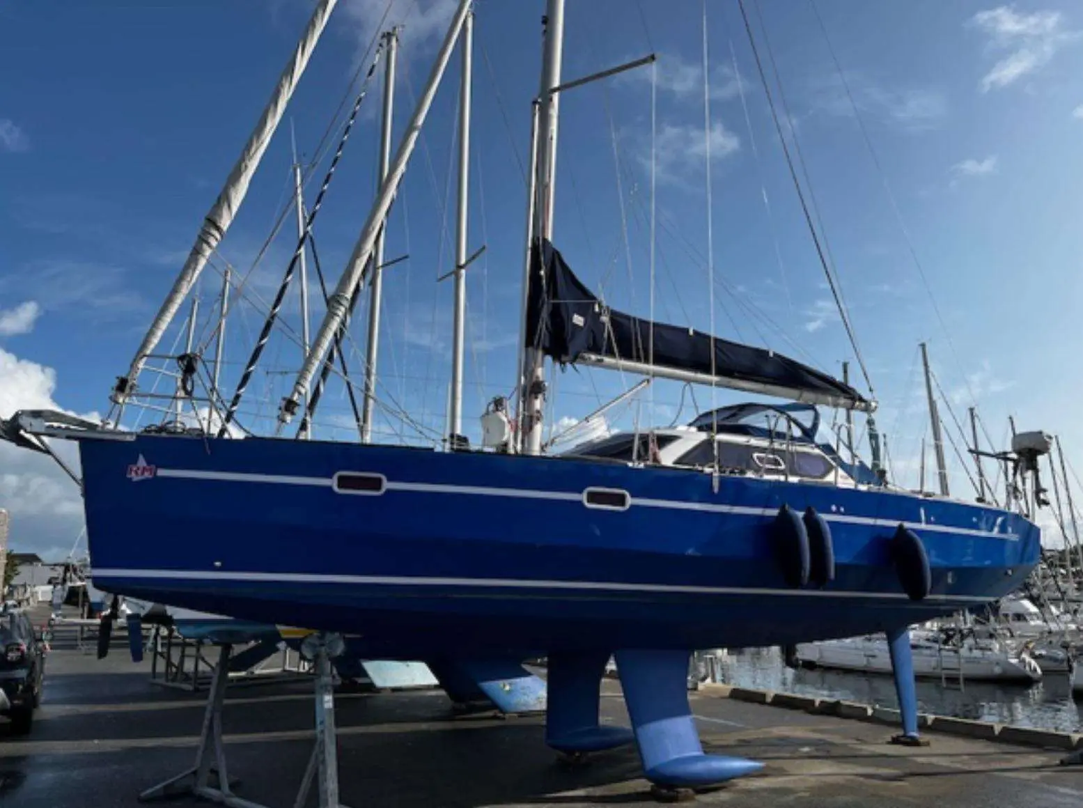 RM Yachts RM 1050 — Voilier bleu à quille, photographié à terre dans un port de plaisance.