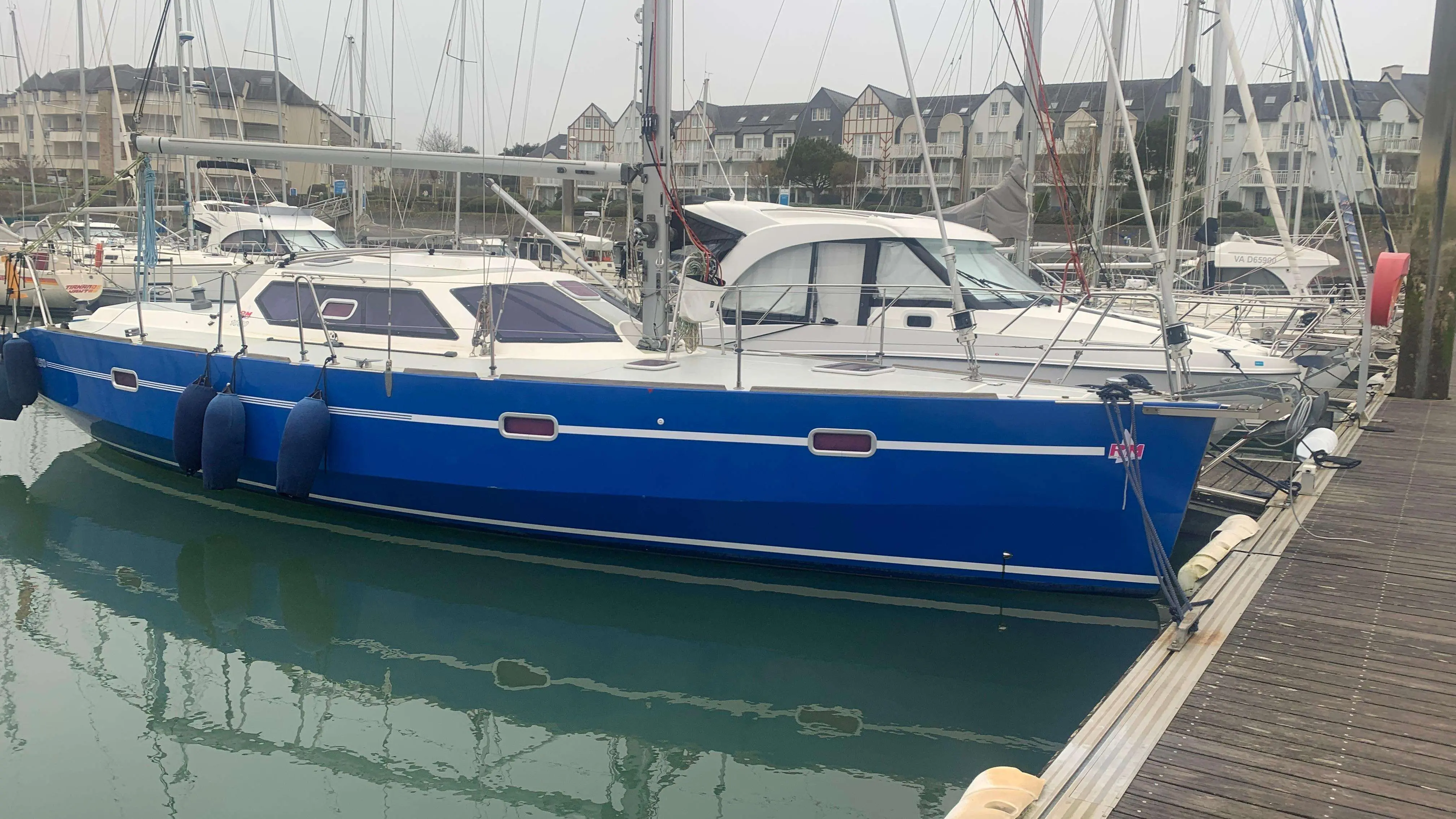 RM Yachts RM 1050 — Voilier bleu amarré dans un port, vu de profil depuis le quai.