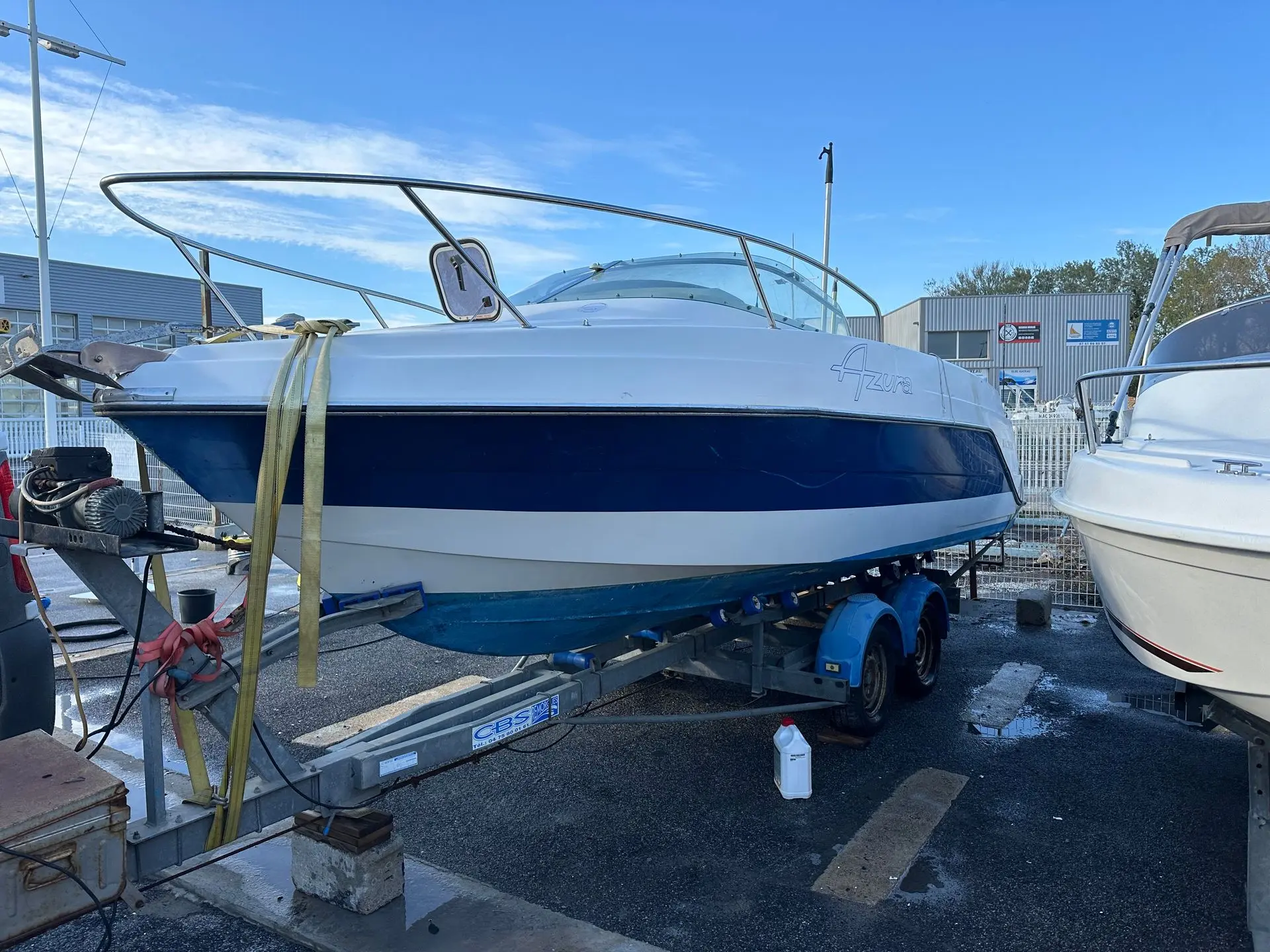Kelt Azura — Bateau à moteur blanc et bleu sur remorque dans une zone de stockage.