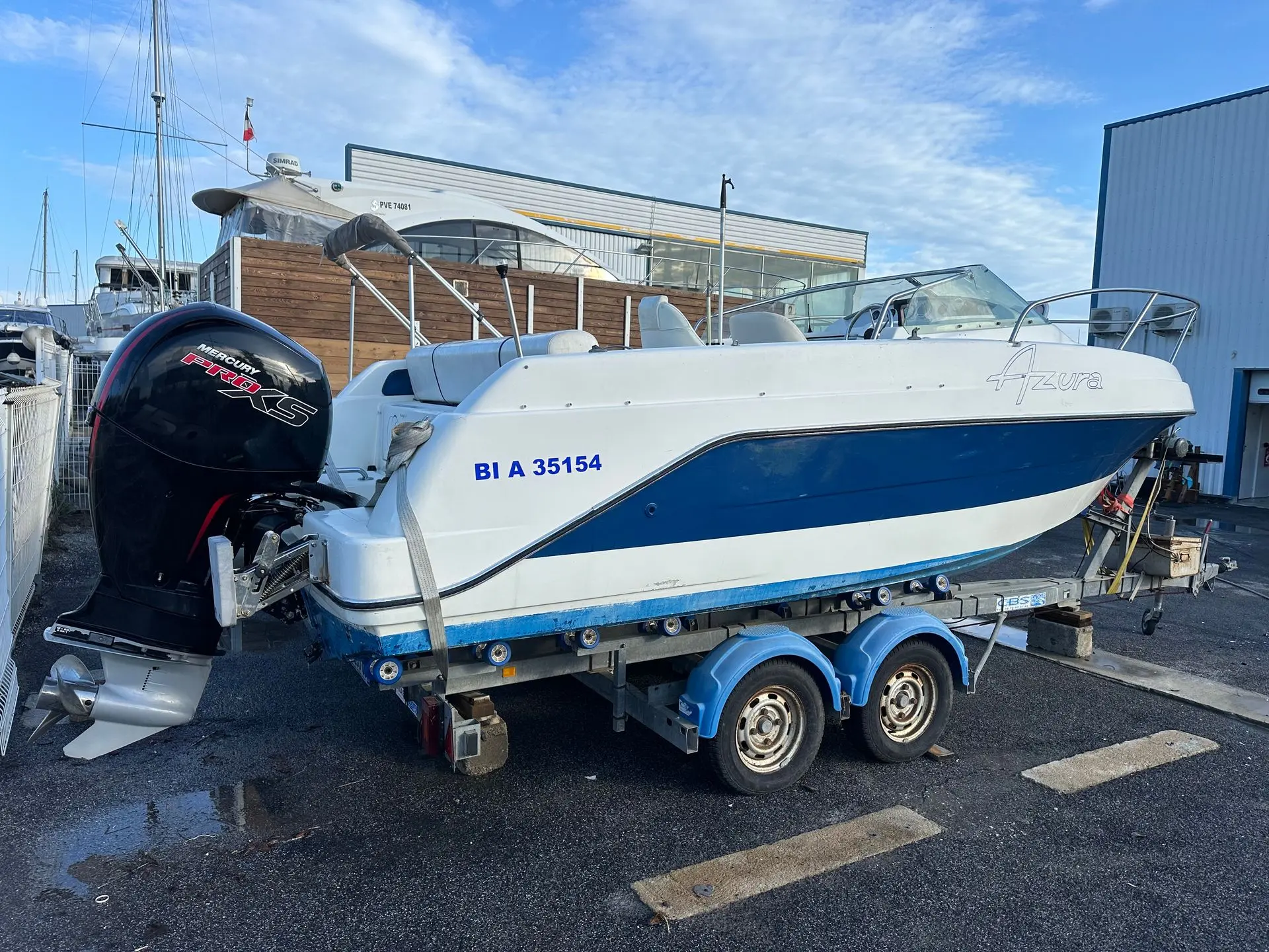 Kelt Azura — Bateau à moteur blanc et bleu posé sur une remorque dans un port.