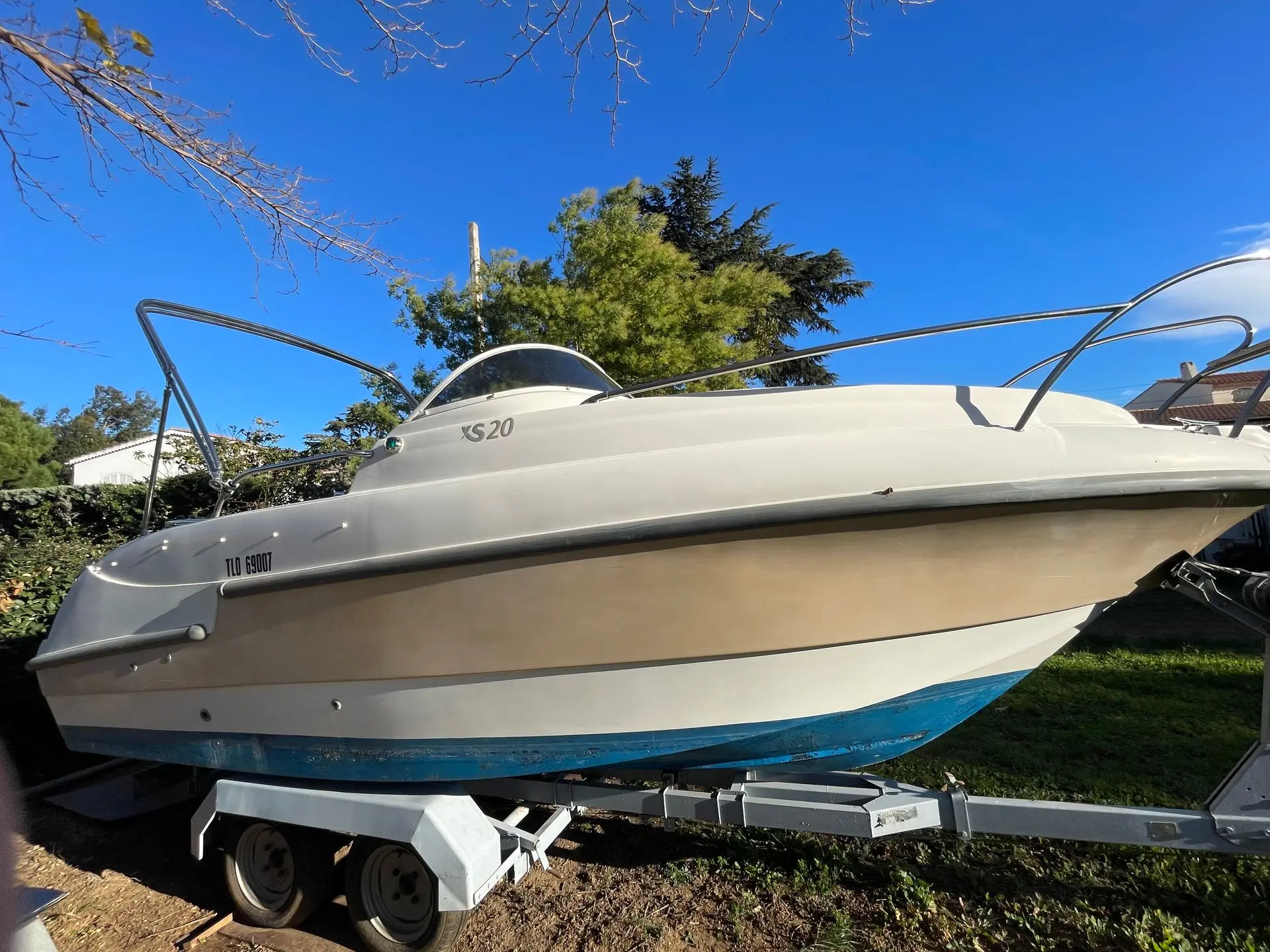 Lexsia XS20 — Bateau à moteur blanc et bleu présenté sur sa remorque, vu de profil.