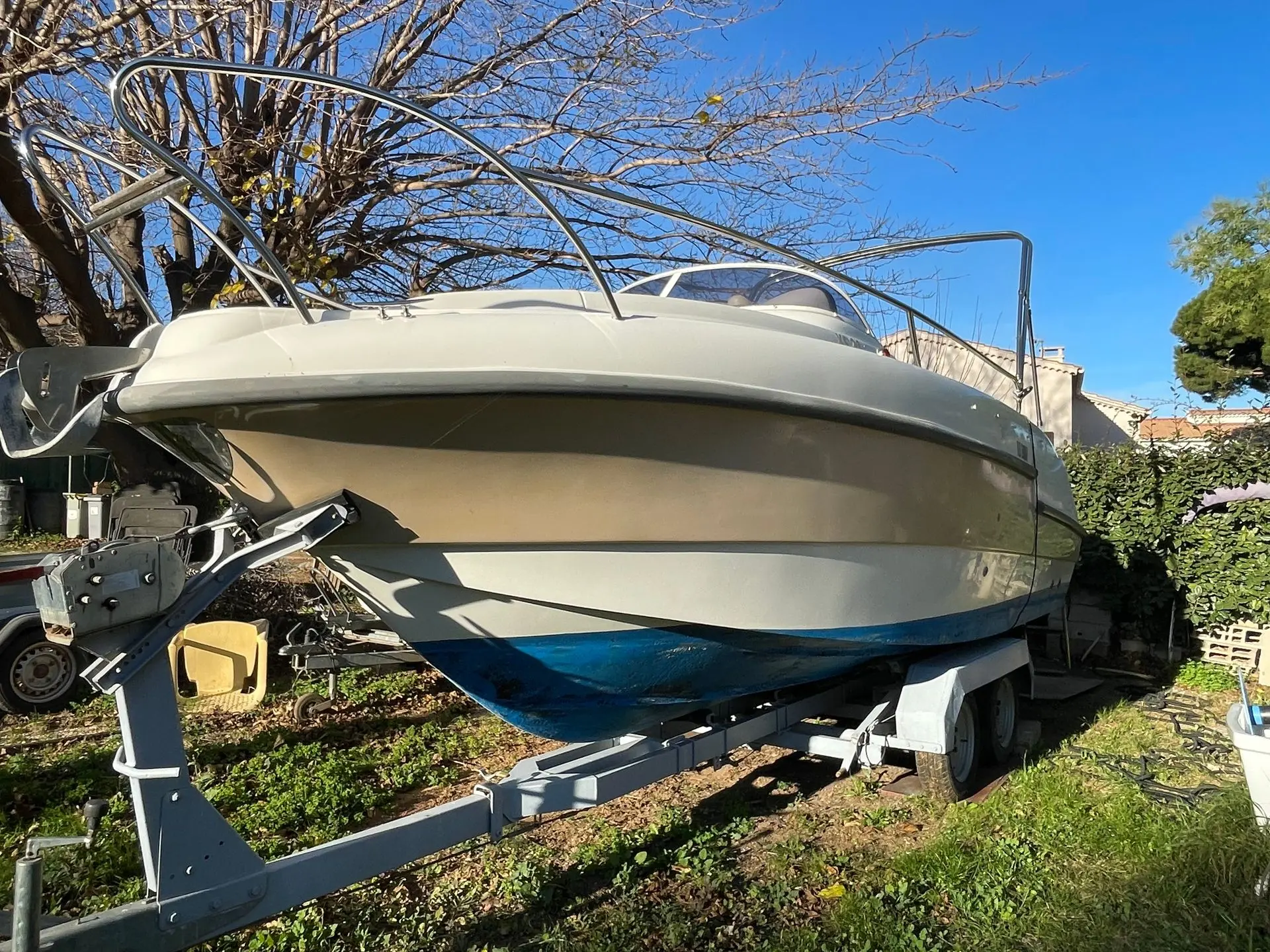 Lexsia XS20 — Bateau à moteur blanc et bleu présenté sur sa remorque dans un jardin.