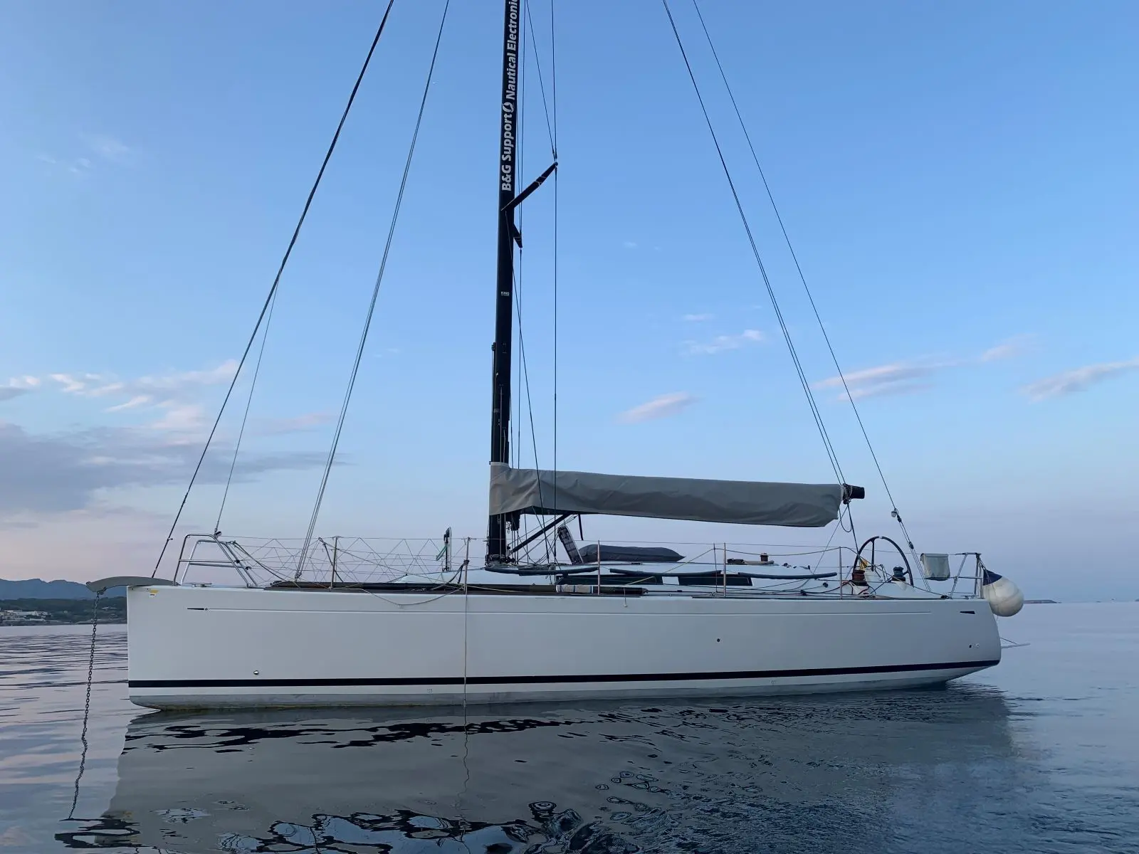Grand Soleil 37 — Voilier blanc vu de profil sur une eau calme, avec grand-voile ferlée.