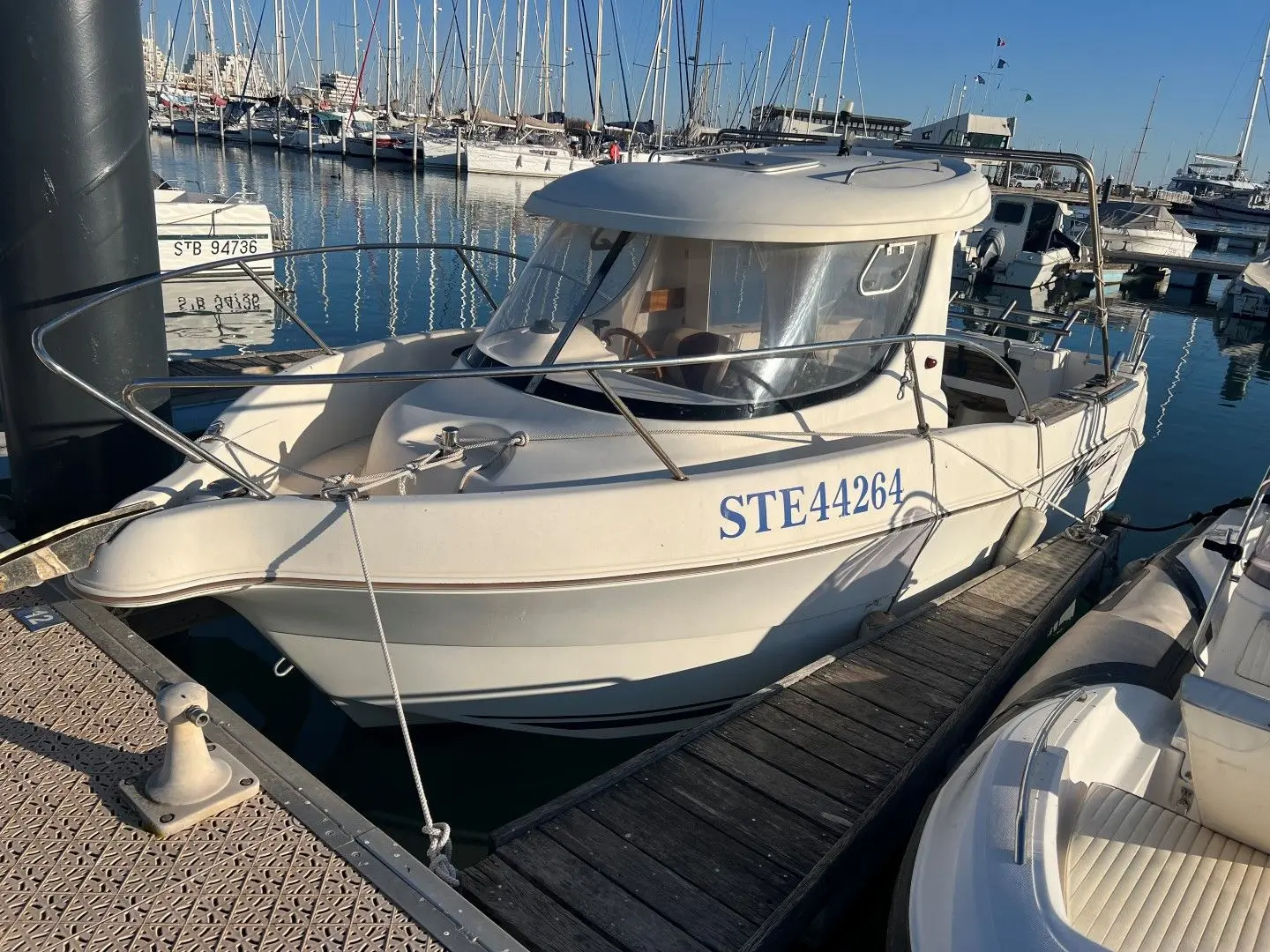 Arvor 215 — Bateau à moteur blanc amarré dans un port de plaisance, vu de trois quarts avant.