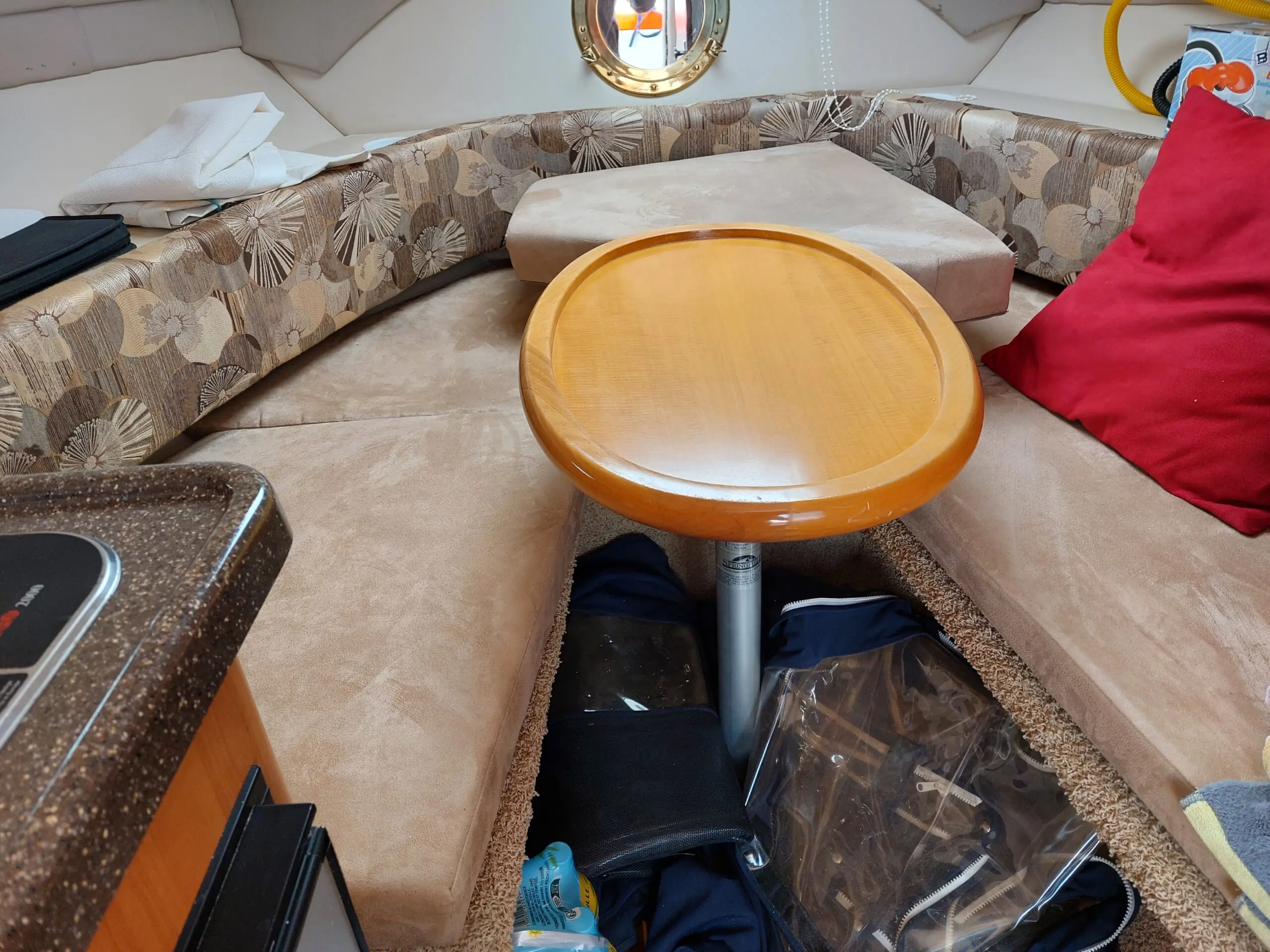 Glastron GT 249 — Vue intérieure d'un salon avec banquettes, table centrale et hublot.