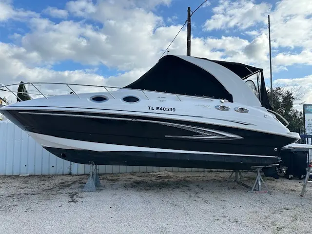 Glastron GS 289 — Bateau à cabine blanc et noir présenté à terre sur supports, vu de trois quarts.