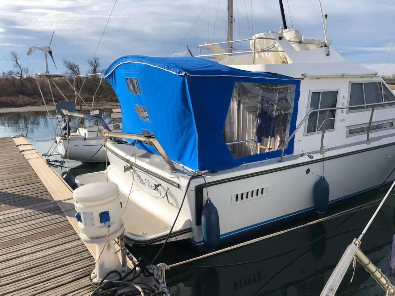 ACM 1100 — Bateau à moteur amarré à un ponton, partiellement couvert d’une bâche bleue.
