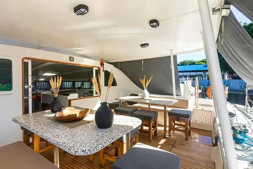Lagoon 570 — Vue du cockpit arrière avec table, banquette et coin repas extérieur.