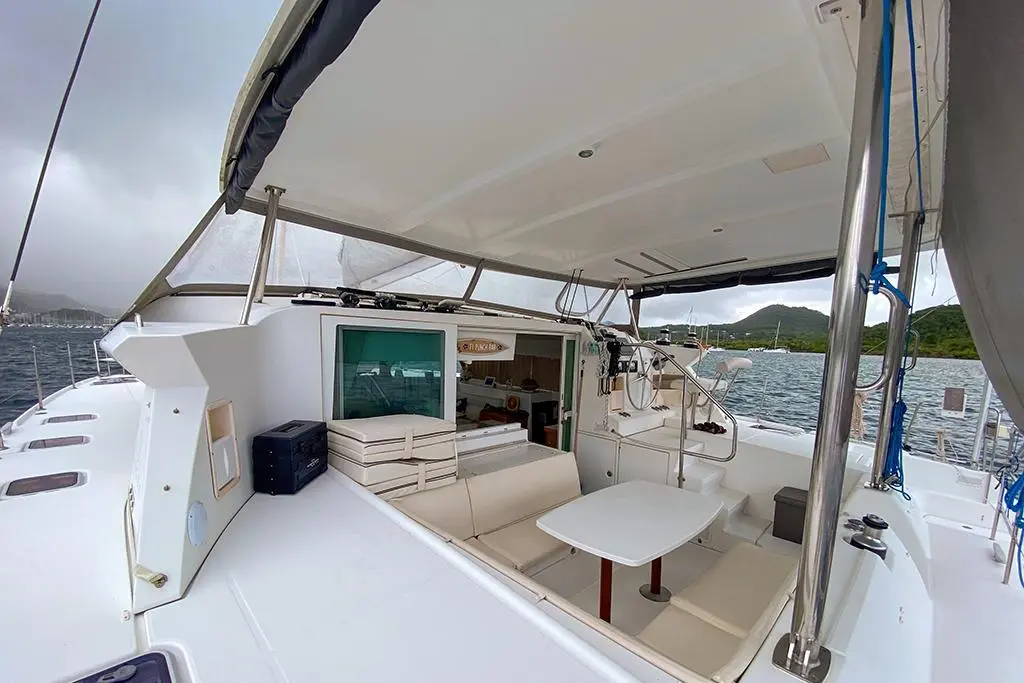 Lagoon 420 — Cockpit couvert d’un catamaran avec salon, table et poste de barre.