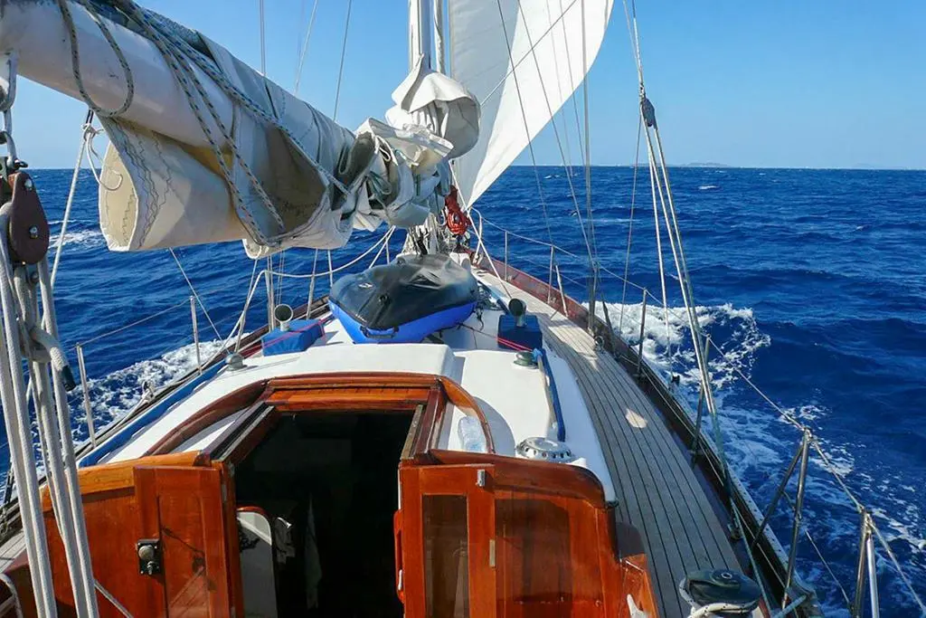 Berthon Yachts Classique Plan Holman — Vue du pont d’un voilier en navigation, avec voiles et mer ouverte.