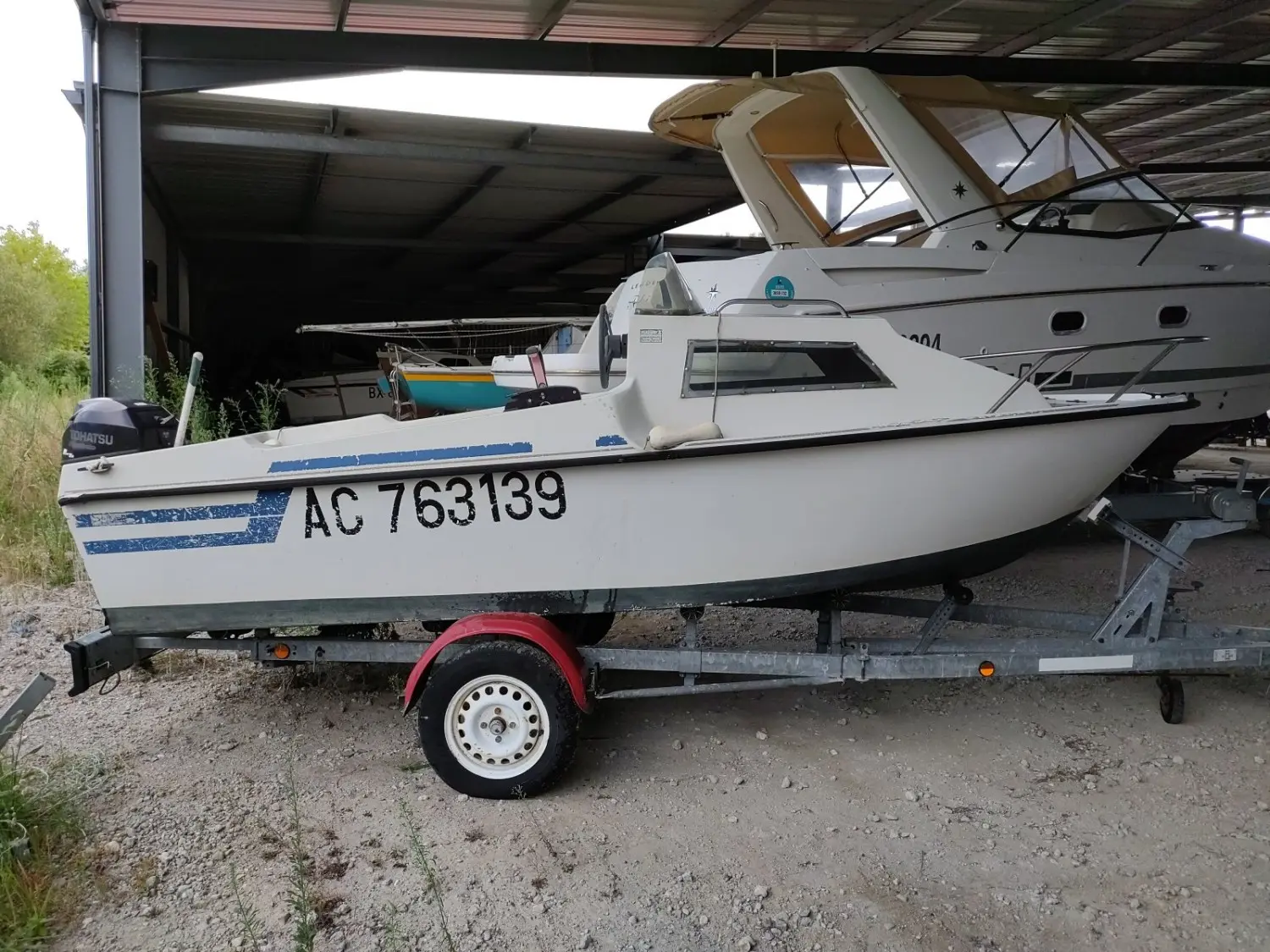 SBPEM S 430 — Bateau à moteur blanc sur remorque, photographié de profil sous un abri.