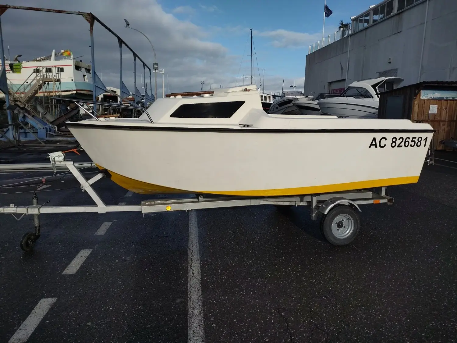 Owens Ocean 400 — Bateau à cabine blanche et liseré jaune, photographié de profil sur sa remorque.
