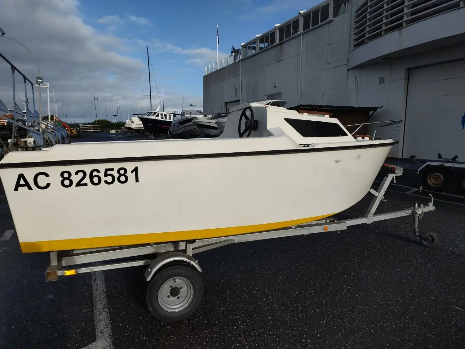 Owens Ocean 400 — Bateau à moteur blanc et jaune présenté sur une remorque dans une zone portuaire.