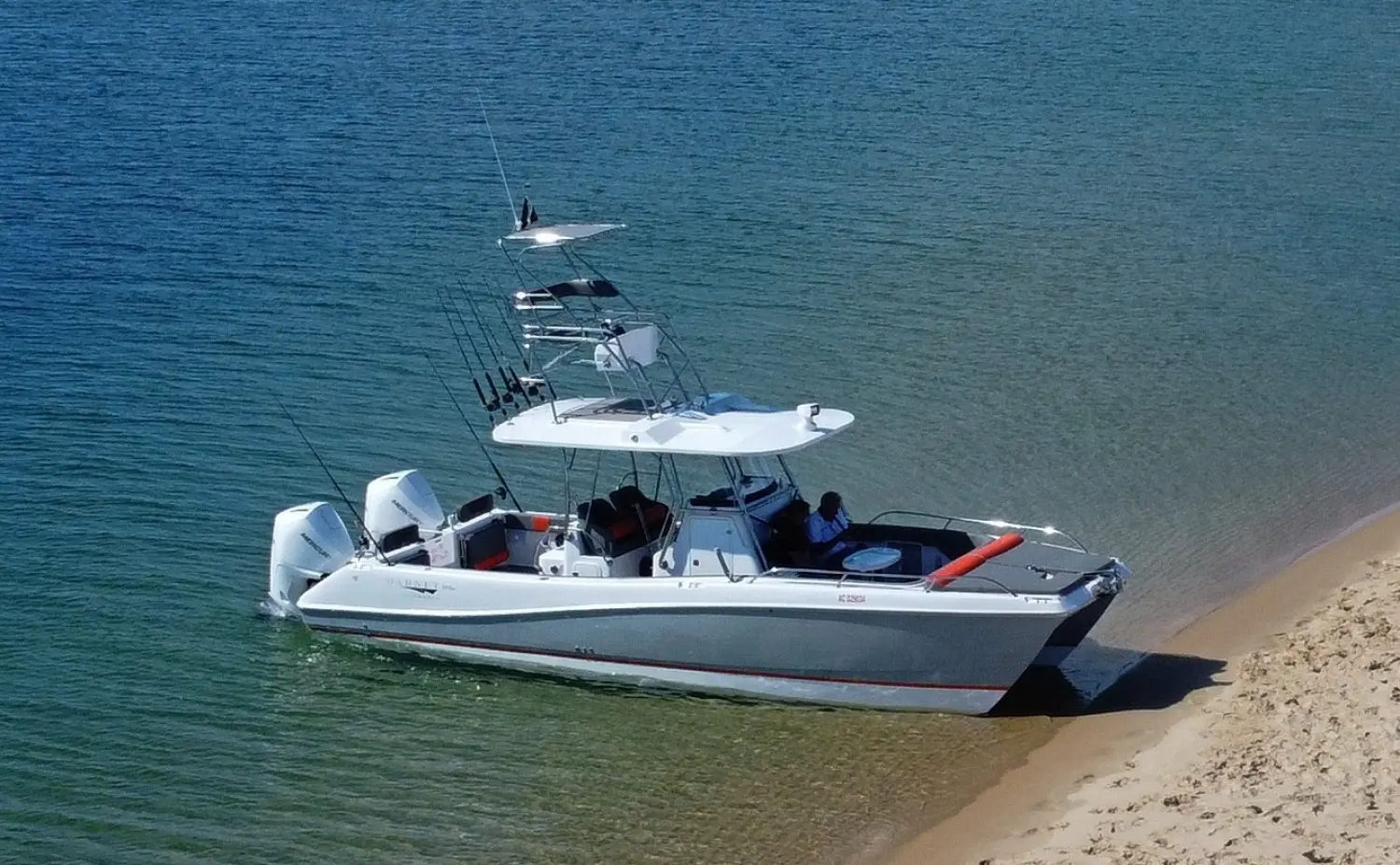 Garnet Offshore 300 HT Fly — Bateau à moteur blanc équipé de deux hors-bord, échoué au bord d'une plage.