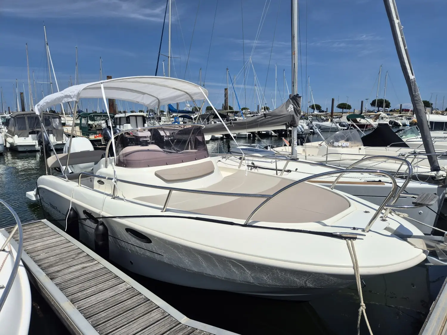 Mingolla Brava 25 WA — Bateau à moteur blanc amarré dans une marina, vu de trois quarts avant.